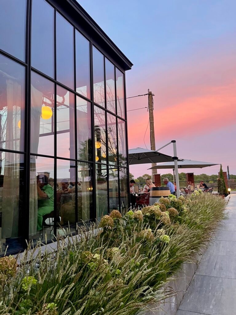 Ober serveert aperitief cocktails op het zonnige terras van Flow Restaurant Lanaken