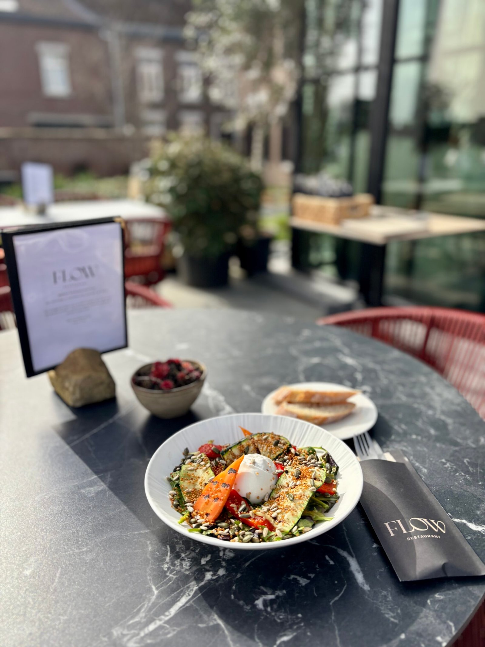 Ober serveert aperitief cocktails op het zonnige terras van Flow Restaurant Lanaken